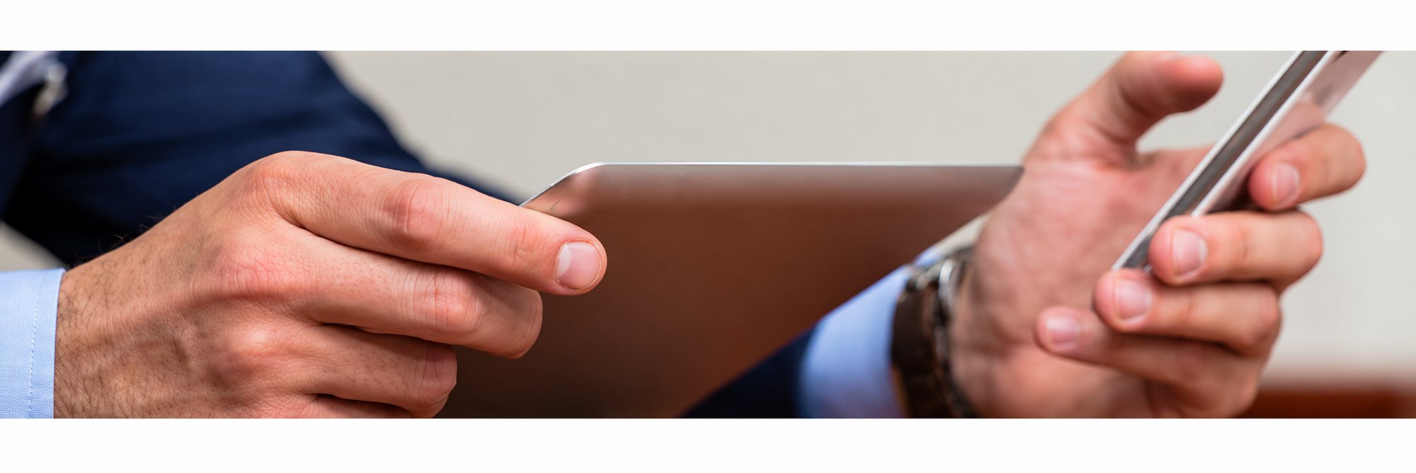 Mains d’un homme en costume tenant une tablette tactile