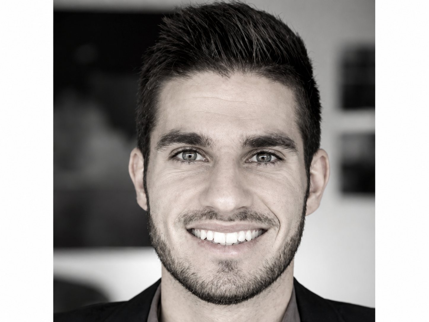 Portrait en noir et blanc d’un homme souriant avec une barbe